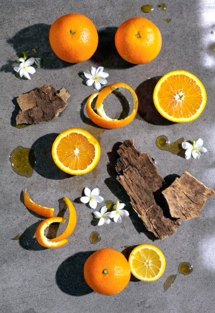 SE-LF Orange, Jasmine & Cedarwood: Bright orange segments, fragrant jasmine flowers, and cedarwood shavings on polished concrete.