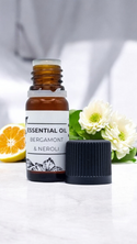 SE-LF Essential Oils: 10ml Bottle resting on a polished surface with bargamot fruit and neroli flowers in the background